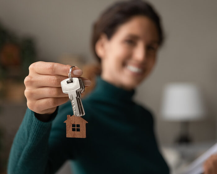 Close,Up,Focus,On,Keys,,Smiling,Woman,Realtor,Selling,Apartment,